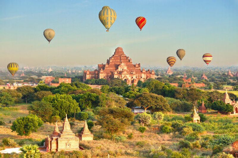 Above temples, pagodas and stupas, hot air balloons fly in the city of Bagan.