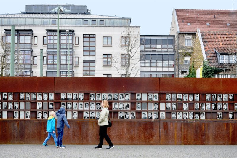 Visitors at the Monument of the Berlin Wall which features photos of people who died during the Cold War.