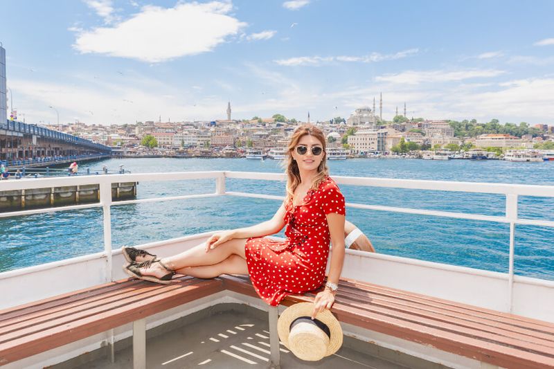 A tourist on the Bosphorous Strait Cruise with a view of the Galata Bridge and the Suleymaniye Mosque.