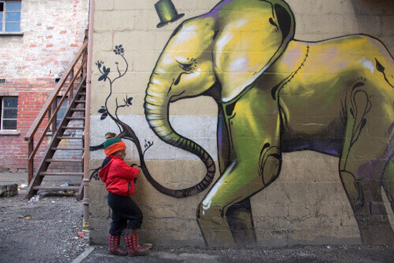 A young boy poses for a photograph next to a painted building in Langa, South Africa.