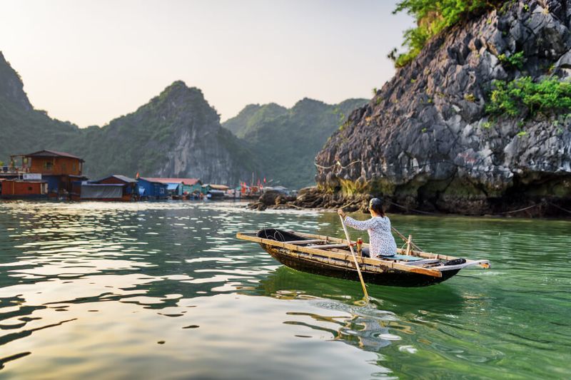 A female water hawker floating in the fishing village in Halong Bay.