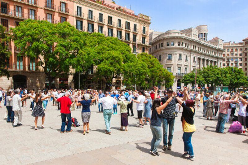 People holding hands and dancing the national Catalonian dance called Sardana at a Plaza in Barcelona.