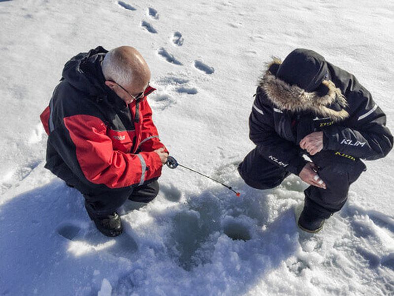 Tourists ice fishing with a veteran fisherman in Inari, Finland.