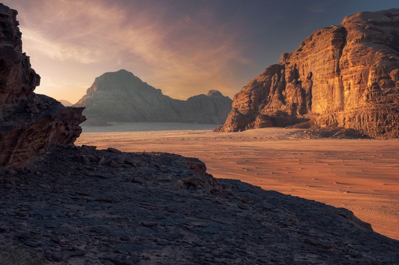 Red desert cliffs and sand in Wadi Rum, capturing the otherworldly setting and rich archaeological history of the Valley of the Moon