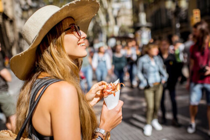 A woman stands with a cone of the local delicacy, Jamon in Spain.