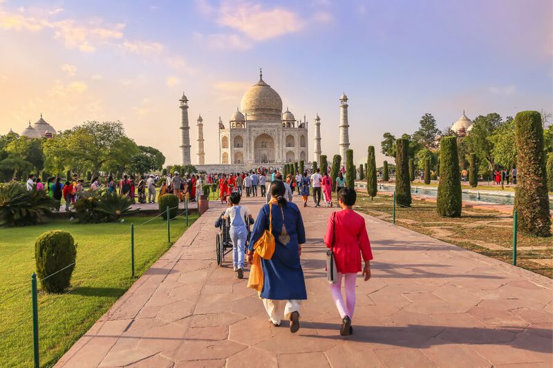 The Taj Mahal mausoleum at sunset with tourists visiting the monument.