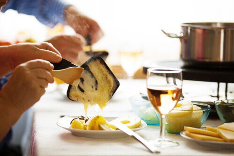 A traditional Swiss meal called Raclette with swiss cheese on top of potatoes.