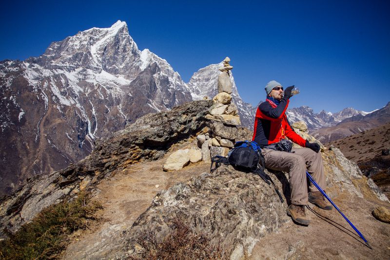 A hiker rests high in the Himalayas, surrounded by Nepal’s majestic peaks