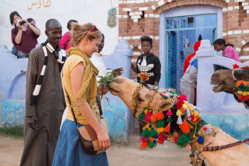 A female tourist feeding a camel in a Nubian Village.