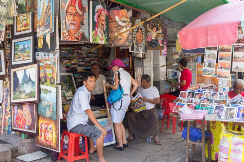 A tourist shopping for authentic Myanmar paintings in a shop.