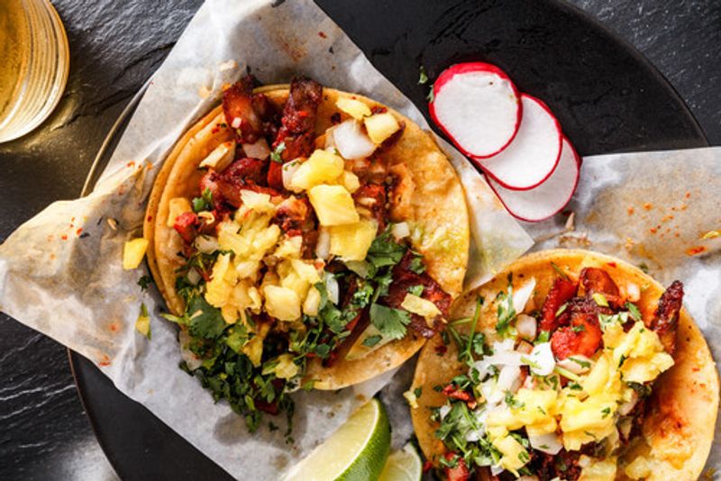 Tacos al pastor laid out on a table.