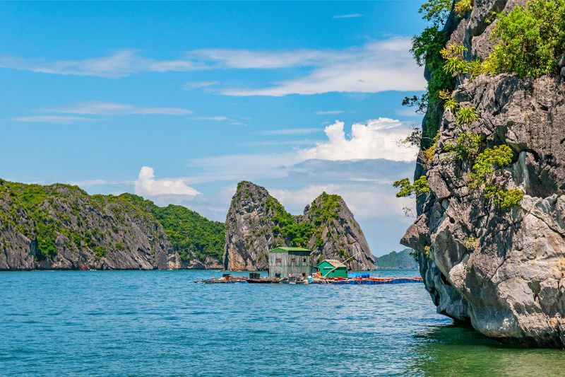 The floating houses with the Karst Mountains visible under the emerald waters of the Gulf of Tonkin.