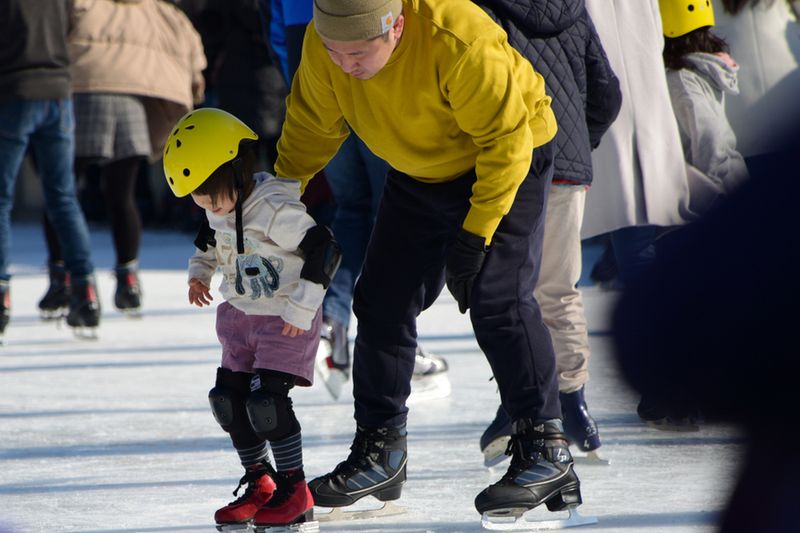 A Japanese father helping his daughter ice skate.