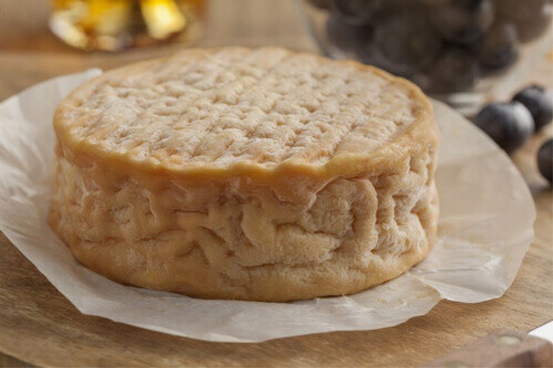 A close up of a whole ripe, creamy Epoisses cheese.