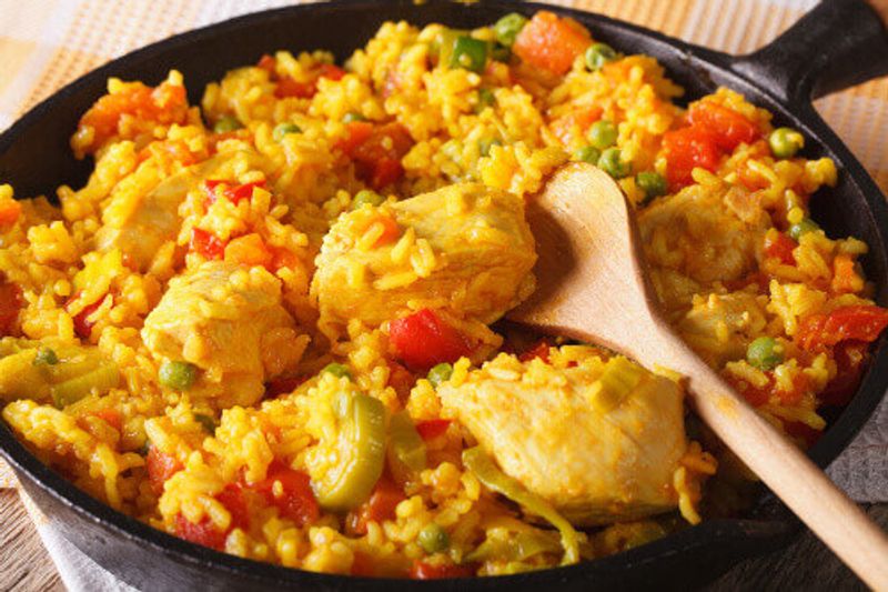 Arroz con pollo,  a rice dish with chicken and vegetables in a frying pan.