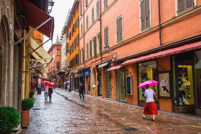 A view of the downtown streets with red portico buildings in Bologna.