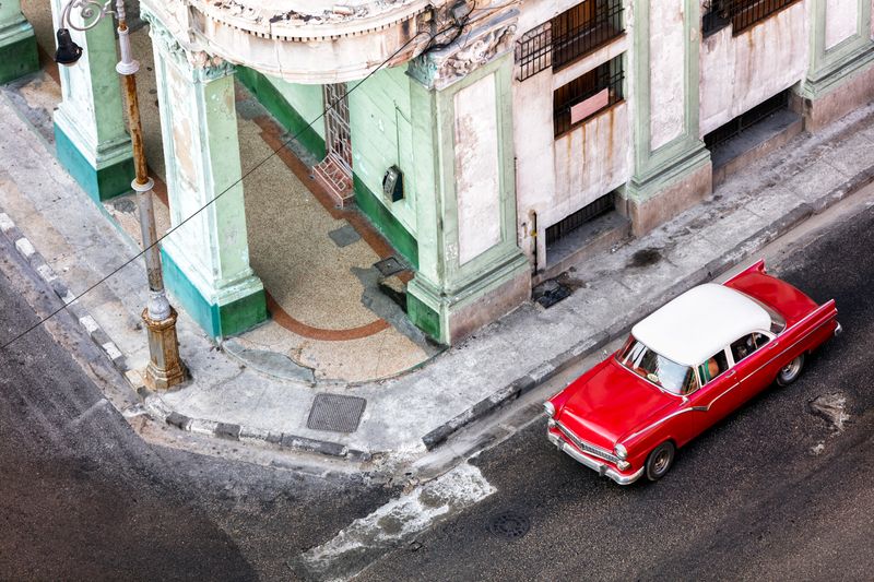 A classic red vintage car cruises through the colourful streets of Havana