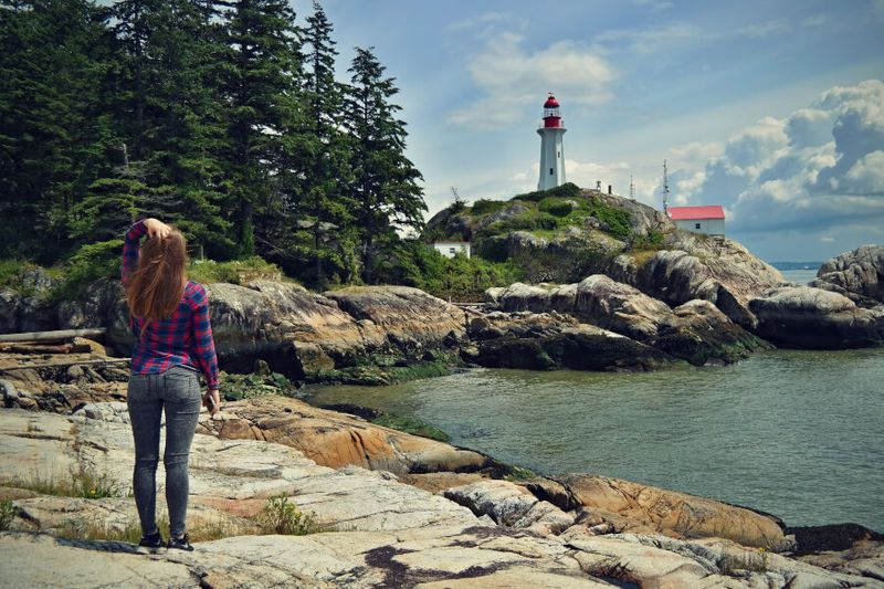 A woman looks up and enjoys the view of the Point Atkinson Lighthouse in Lighthouse Park.