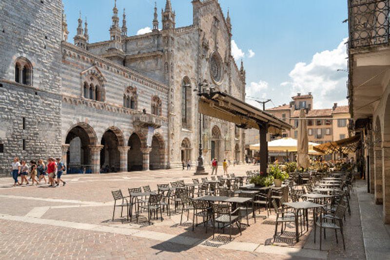 View of Duomo square with a traditional Italian street cafe in the historic centre of Como.