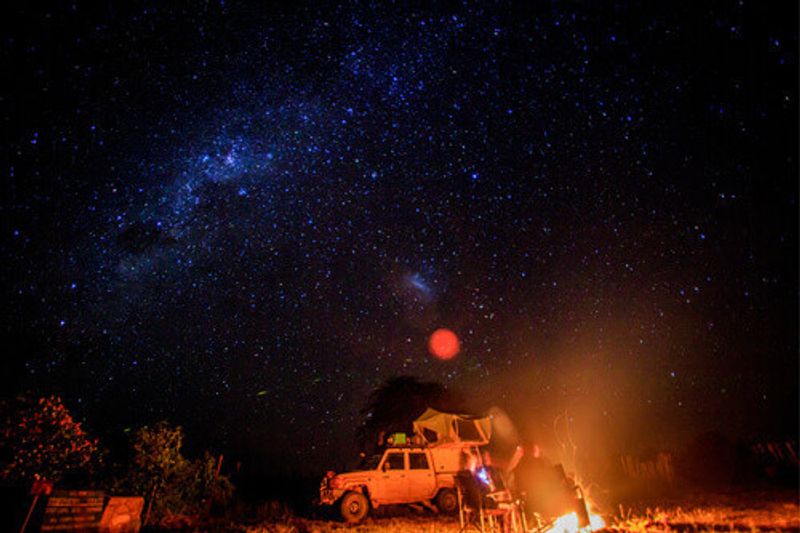 Camping at night with a fire and stars visible in the Hwange National Park.