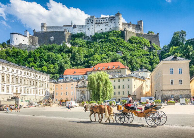 The historic city of Salzburg with a traditonal horse-drawn Fiaker Carriage and the famous Hohensalzburg Fortress in view.