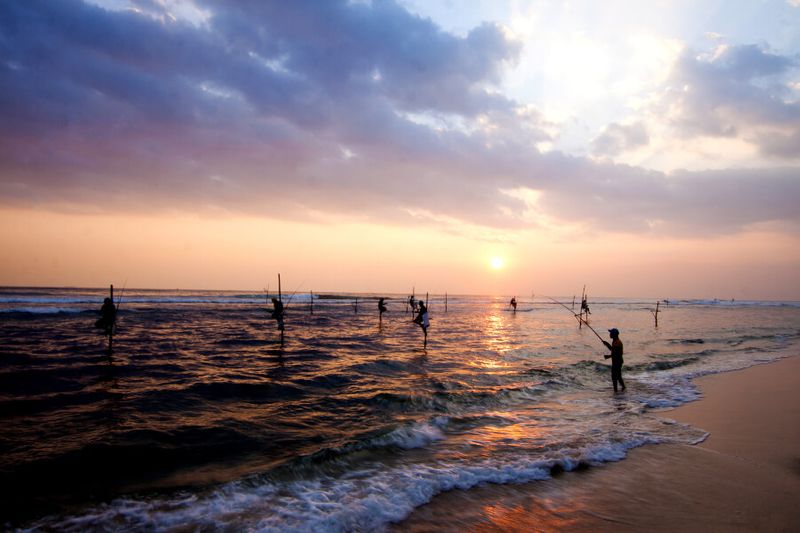 Silhouettes of stilt fishermen at sunset in Galle