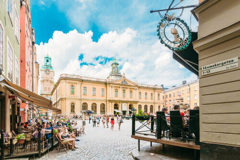 Tourists dining with the Swedish Academy and Nobel Museum in the background in Stortorget Square in Gamla Stan, Stockholm.