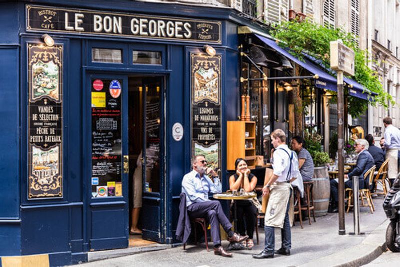Parisians and tourists enjoy food and drinks at a French Cafe in Paris, France.
