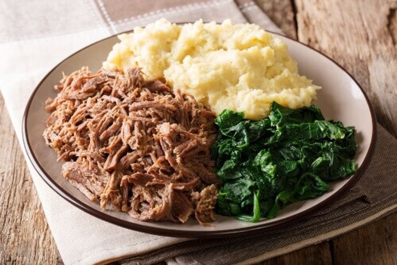 A Zimbabwean meal consisting of stewed beef with pap porridge and spinach.