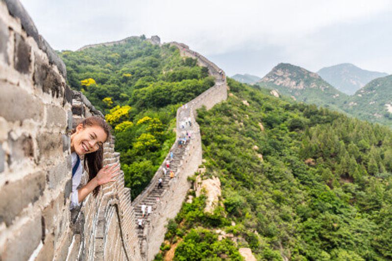 Tourist having fun and waving at the Great Wall of China in Badaling.