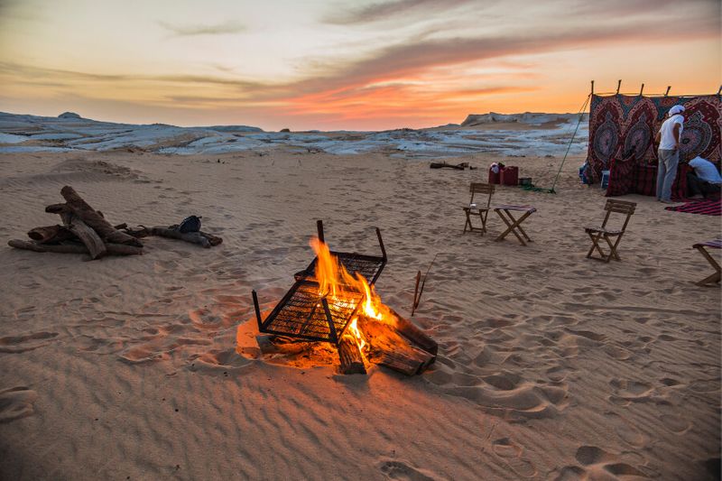 Camping in the Sahara desert with tents and bonfire early in the morning.