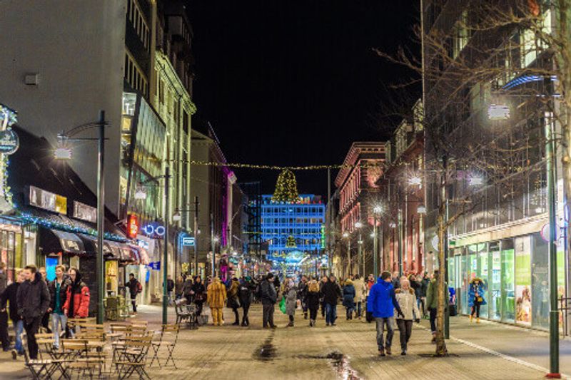 People walking in the Austurstraeti street on a winter evening.