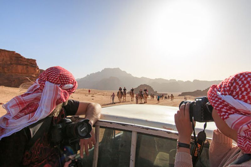 Tourists taking a picture from a car driving through the Wadi Rum Desert in Jordan.