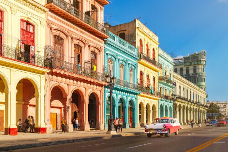 Street scene with classic old cars and colourful Spanish colonial buildings in downtown Havana.