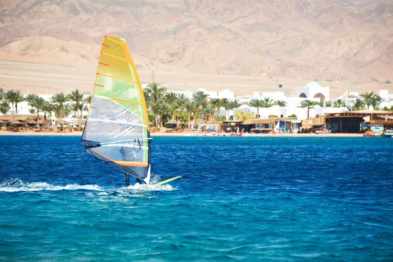 A windsurfer sailing off the blue coast of Dahab