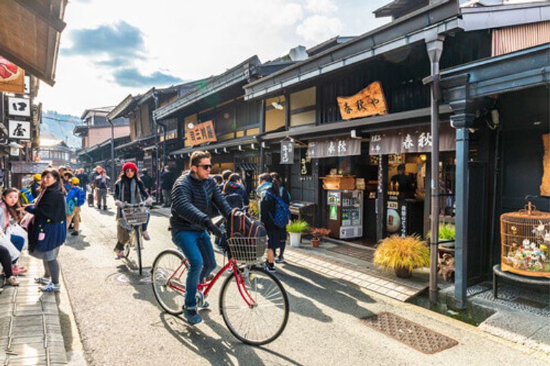 Person riding bike in the busy Takayama Old Town, Japan.