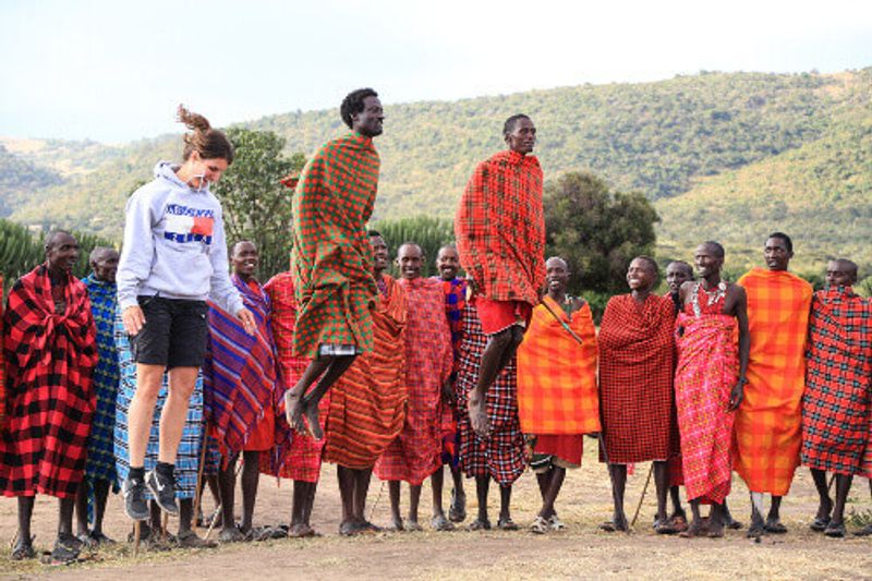 Tourist jumps with Masai warriors at a cultural ceremony in the Masai Mara National Park.