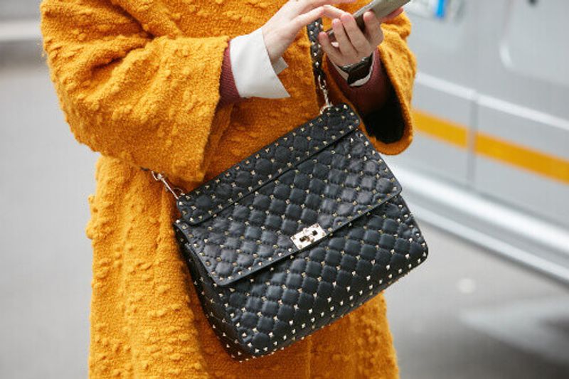 Woman with a black designer leather bag in Milan.
