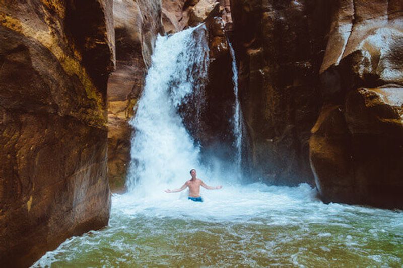 Man relaxing under a waterfall in Wadi Mujib, Jordan.