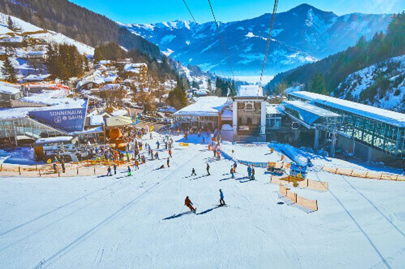 The Alps with people skiing and snowboarding in Zell Am See.