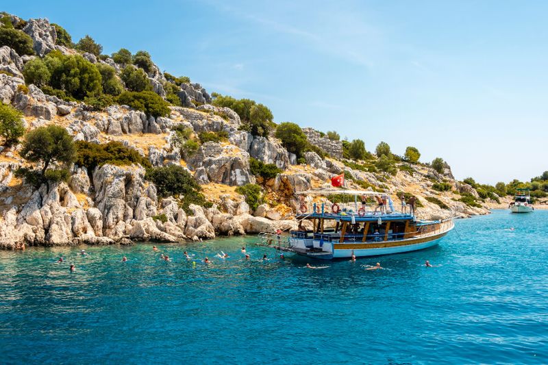 People swimming on the Kekova district coast with a Gulet boat.