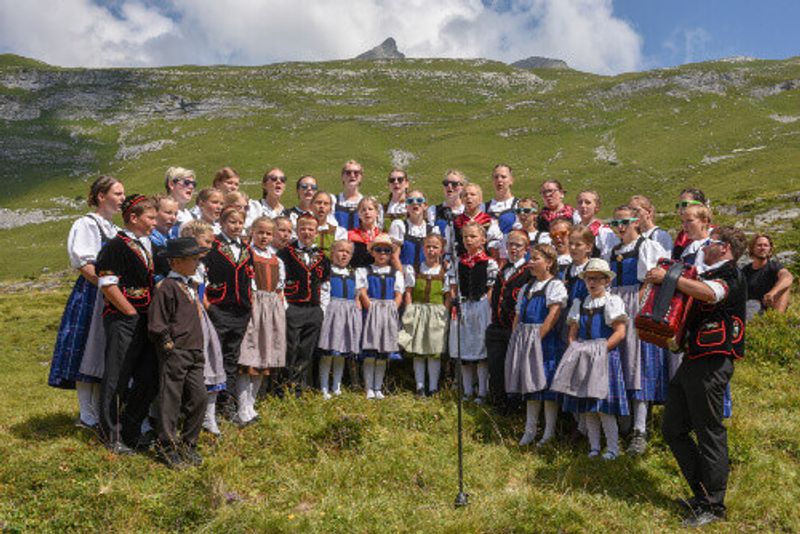 People wearing traditional swiss clothes yodelling at Engstlenalp on the Swiss Alps.