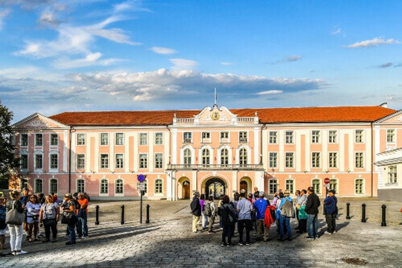 Two tour groups visit the exterior facade of the Tallinn Parliament Building part of the Tallinn Castle.