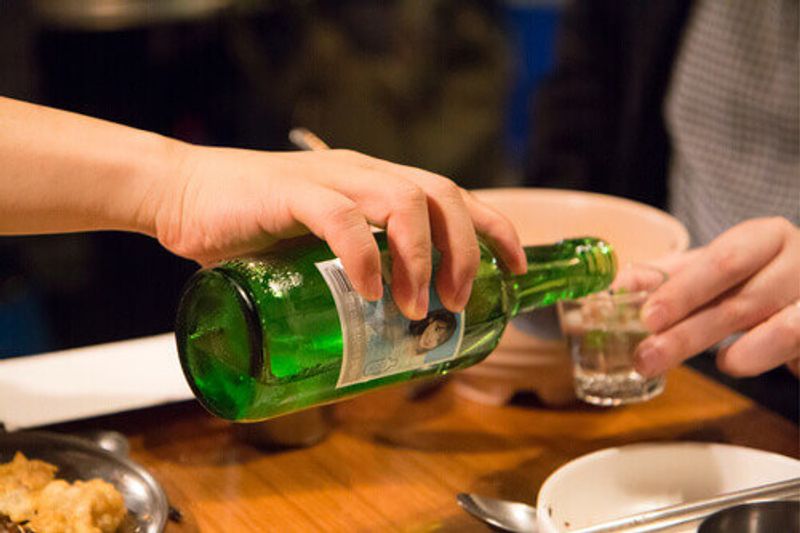 Soju pouring from bottle into glass at a party in Seoul, South Korea.