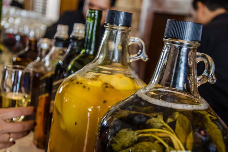 Glass bottles of Pisco with macerated fruits and vegetables at a bar in Peru.