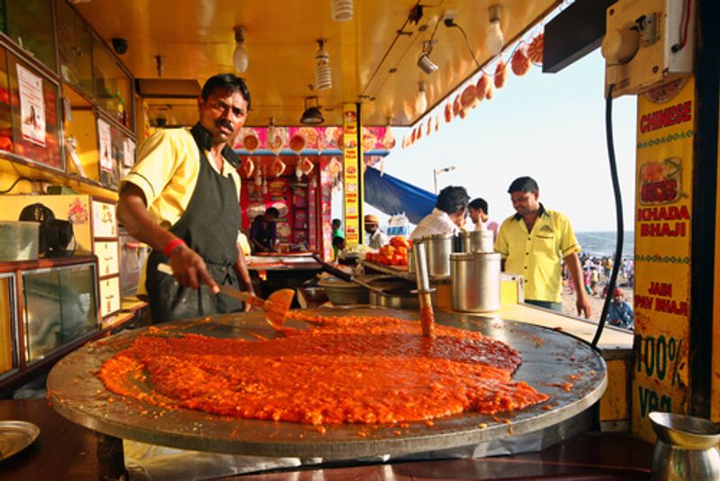 A local man cooks in a street food stall.