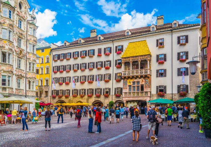 People admiring the famous Goldenes Dachl next to the Helblinghaus in Innsbruck.