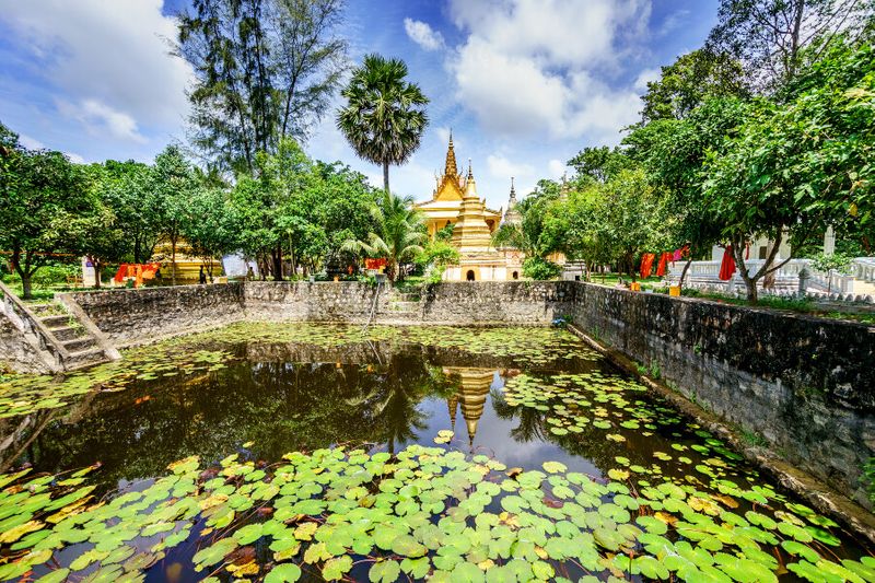 Exterior view of a Khmer Pagoda near a pond in An Giang Province.