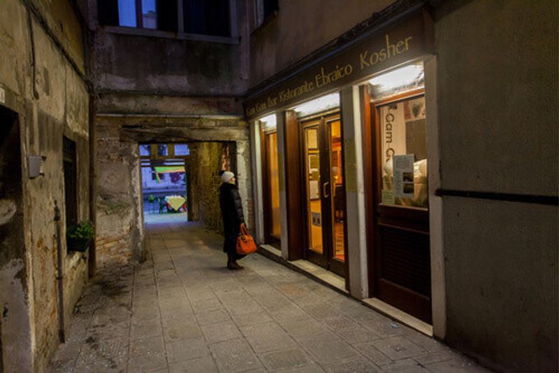 A woman looks into the window of the kosher Gam Gam Bar in the Jewish Quarter of Venice.