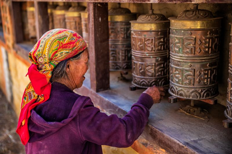 An elderly Tibetan woman turns prayer wheels in Upper Mustang, preserving centuries-old Buddhist traditions in Nepal